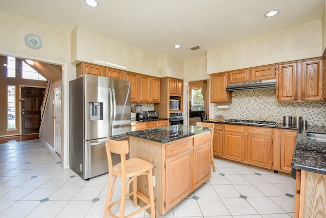 kitchen featuring visible vents, a center island, under cabinet range hood, dark stone counters, and appliances with stainless steel finishes