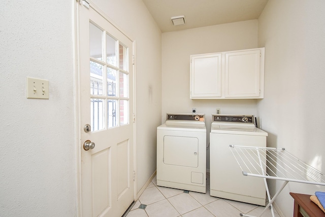 laundry area featuring washer and dryer, light tile patterned flooring, cabinet space, and visible vents