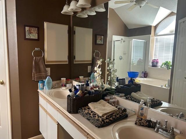 full bathroom featuring a bath, a shower stall, vaulted ceiling, and a sink