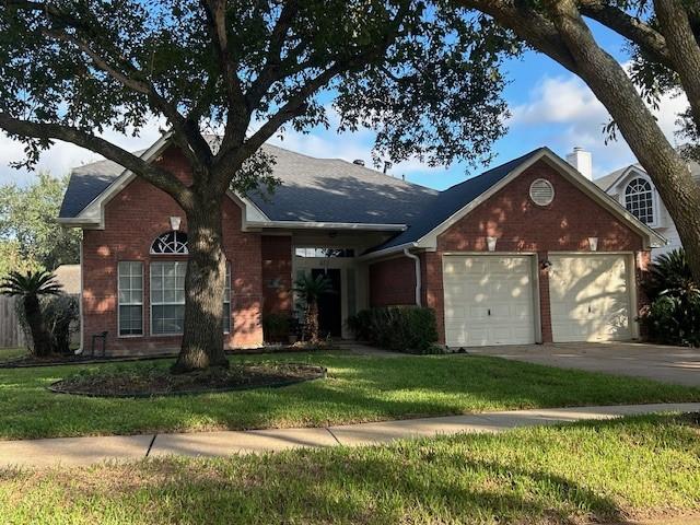 view of front of home featuring brick siding, concrete driveway, a chimney, an attached garage, and a front yard