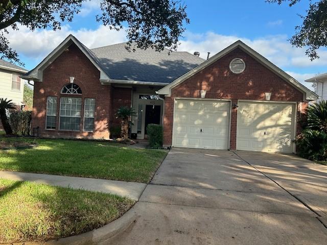 view of front of home with a garage, driveway, a front lawn, and brick siding