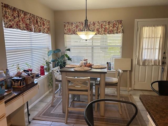 dining area with light tile patterned flooring, a wealth of natural light, and baseboards