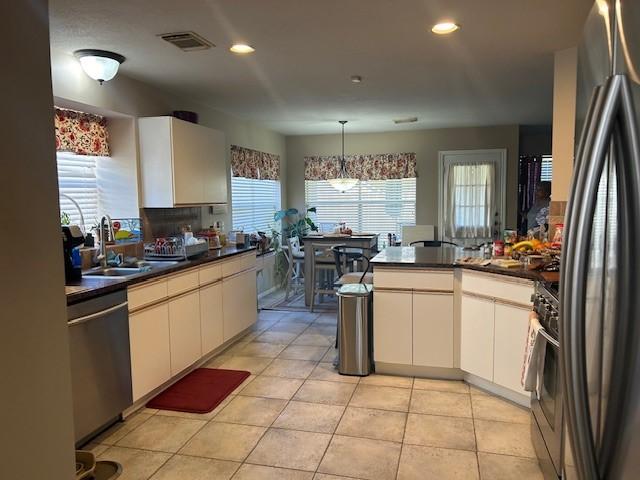 kitchen with dark countertops, a peninsula, stainless steel appliances, and a sink