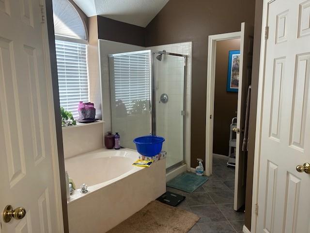 bathroom featuring a garden tub, vaulted ceiling, a shower stall, and tile patterned floors