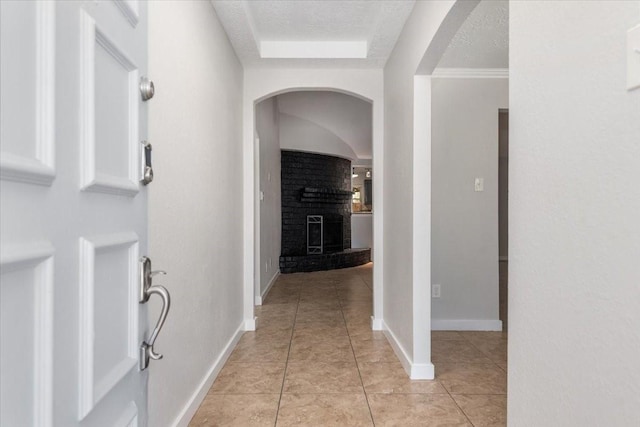 hall with a textured ceiling, light tile patterned floors, and baseboards