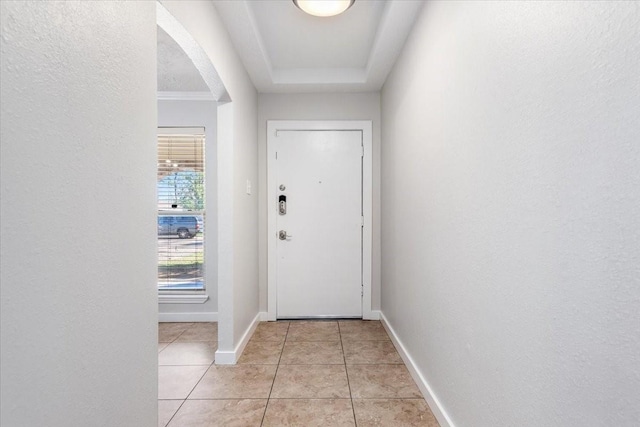 doorway featuring light tile patterned floors, arched walkways, and baseboards