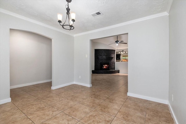 unfurnished dining area featuring a textured ceiling, ceiling fan with notable chandelier, a fireplace, visible vents, and crown molding