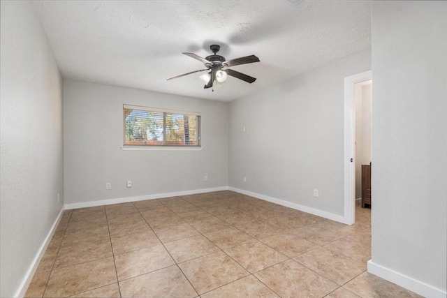 empty room with a textured ceiling, light tile patterned floors, a ceiling fan, and baseboards