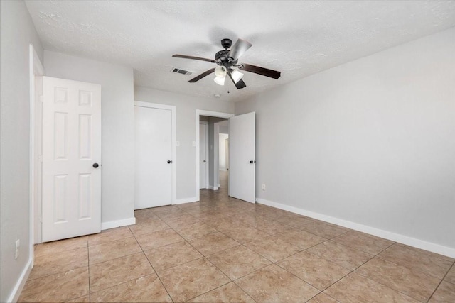 unfurnished bedroom with a textured ceiling, light tile patterned flooring, visible vents, and baseboards