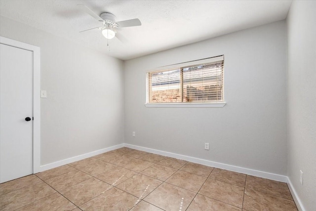 spare room featuring light tile patterned flooring, ceiling fan, and baseboards