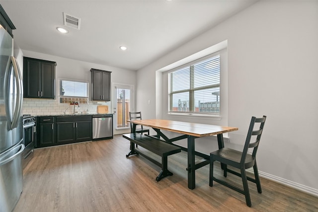 kitchen featuring stainless steel appliances, visible vents, backsplash, light wood-style floors, and a sink