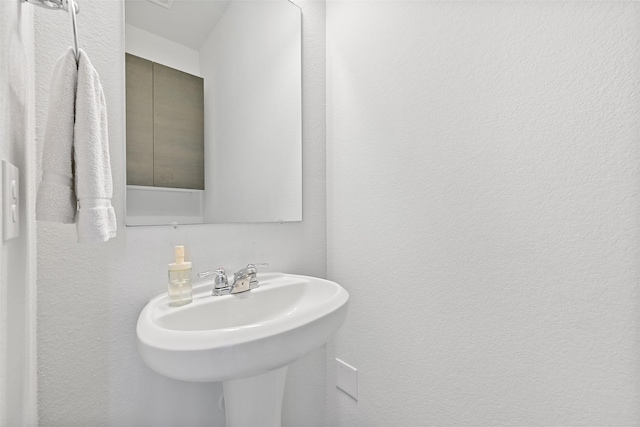 bathroom with a textured wall and a sink