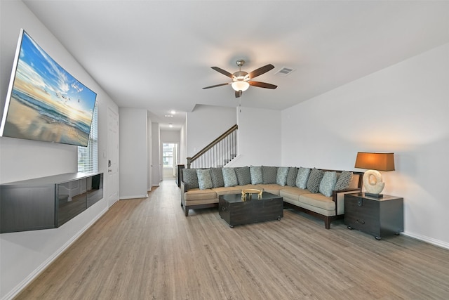 living area with ceiling fan, stairs, baseboards, and wood finished floors