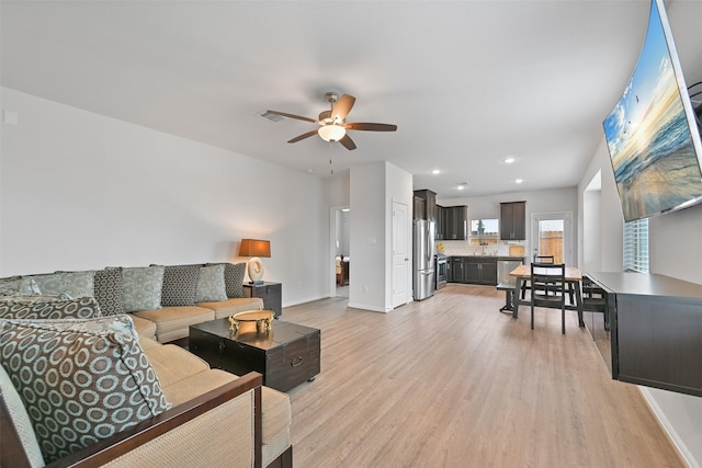 living room with a ceiling fan, recessed lighting, baseboards, and light wood finished floors