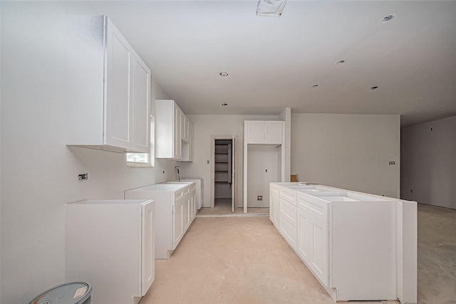 kitchen featuring a kitchen island, washer / dryer, white cabinetry, and unfinished concrete flooring