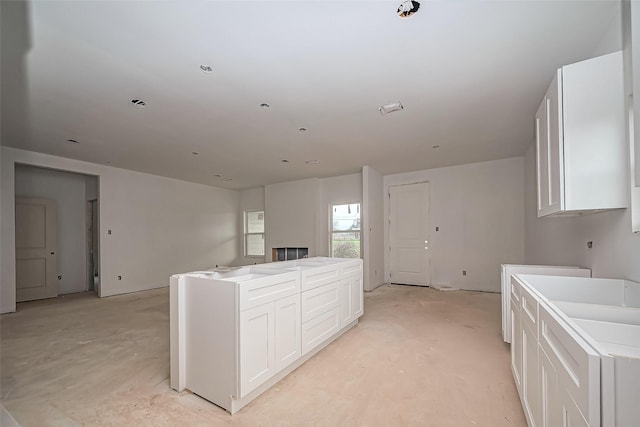 kitchen with open floor plan, white cabinets, unfinished concrete flooring, and a center island