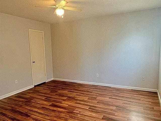 empty room with a ceiling fan, baseboards, and dark wood-style flooring