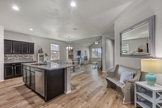 kitchen with light wood finished floors, visible vents, light stone countertops, stainless steel dishwasher, and a sink