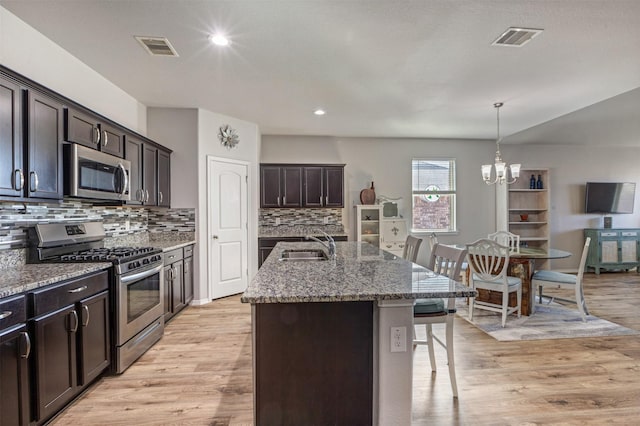 kitchen featuring light stone counters, visible vents, stainless steel appliances, and a sink