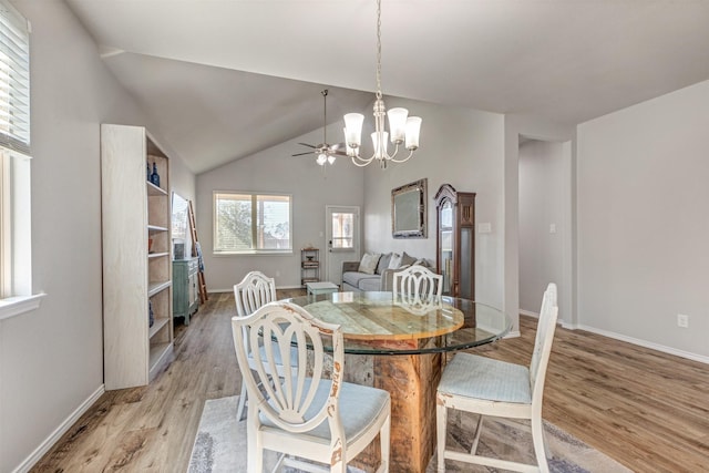 dining room with lofted ceiling, light wood-style flooring, baseboards, and ceiling fan with notable chandelier