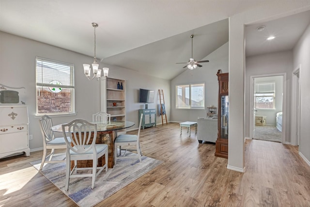 dining area with lofted ceiling, ceiling fan with notable chandelier, light wood-type flooring, and baseboards