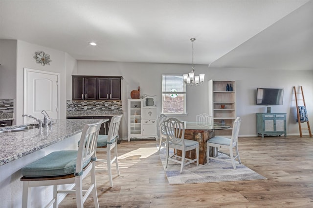 dining area featuring light wood-style flooring, baseboards, a notable chandelier, and recessed lighting