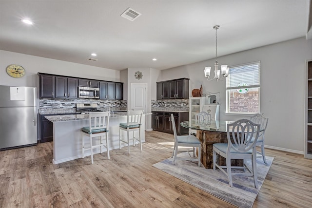 kitchen featuring a chandelier, a kitchen island with sink, visible vents, appliances with stainless steel finishes, and light wood-type flooring