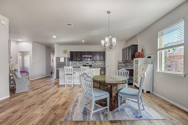 dining area with a chandelier, light wood-type flooring, and baseboards