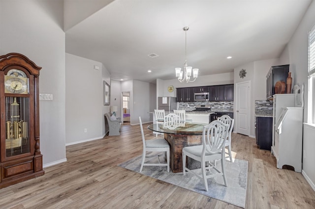 dining area featuring light wood-type flooring, baseboards, a chandelier, and recessed lighting