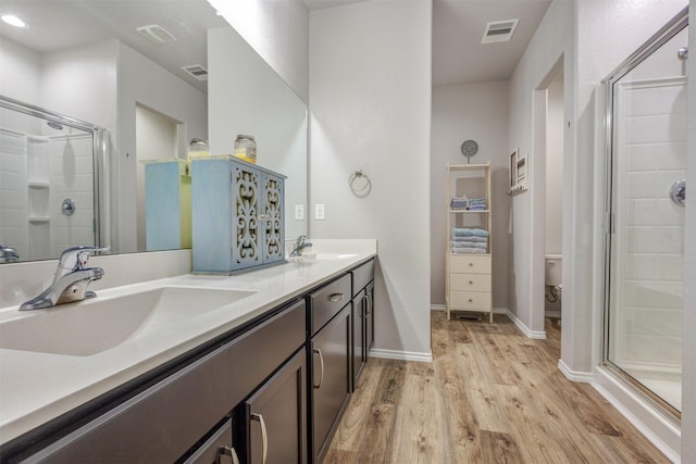 full bath with a stall shower, visible vents, a sink, and wood finished floors