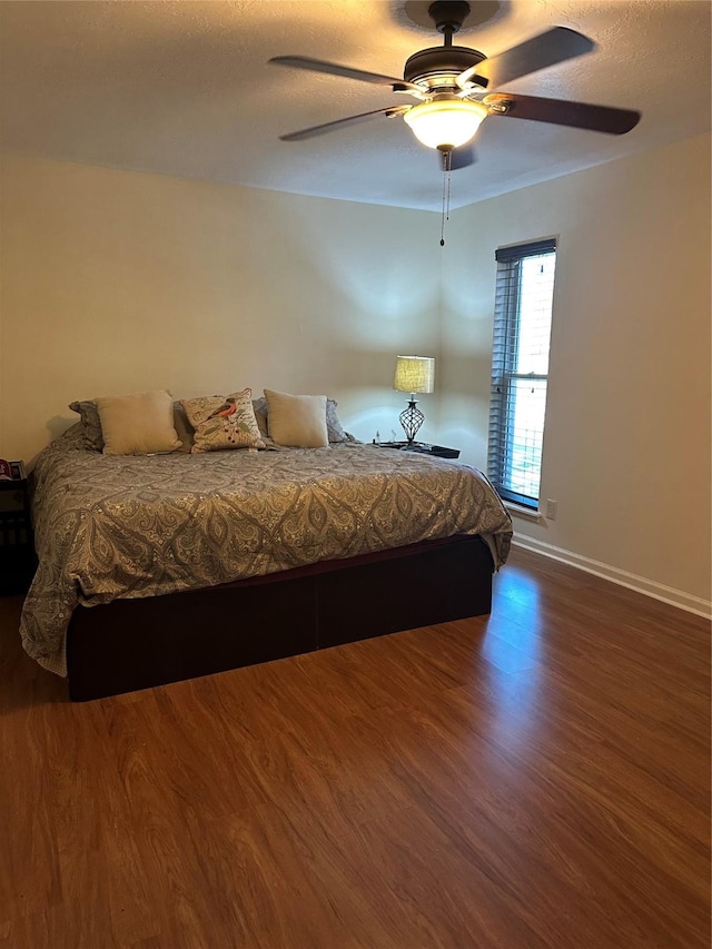 bedroom featuring a ceiling fan, a textured ceiling, baseboards, and wood finished floors