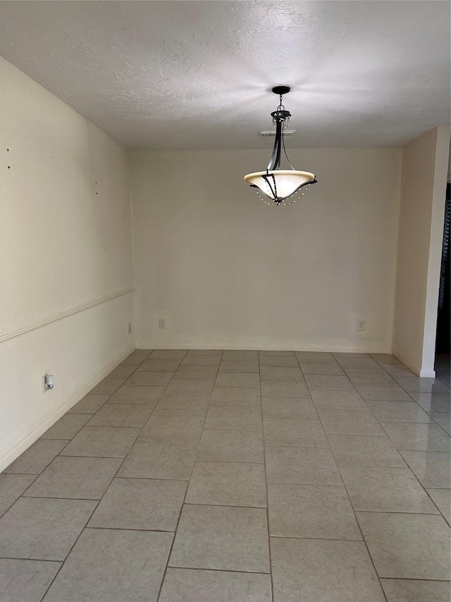 spare room with light tile patterned flooring, a textured ceiling, and baseboards