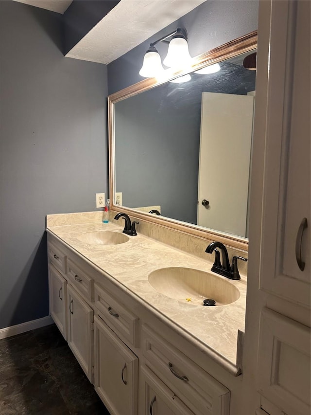 full bath with double vanity, baseboards, and a sink