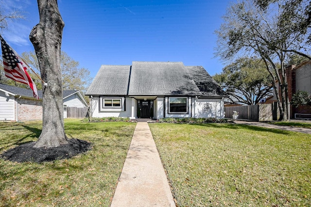 view of front of property with a shingled roof, a front yard, and fence