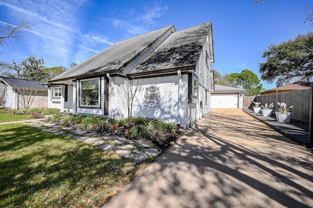 view of front of property featuring an outbuilding, fence, a front yard, and a detached garage