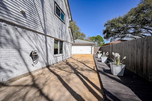 view of side of property featuring brick siding, an outdoor structure, and fence