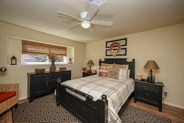 bedroom featuring wood finished floors, visible vents, baseboards, ceiling fan, and a textured ceiling