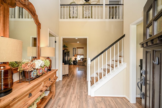 foyer entrance featuring stairs, a high ceiling, baseboards, and wood finished floors