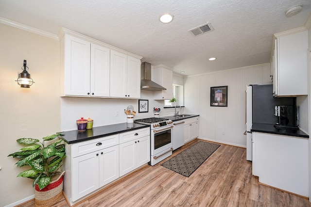 kitchen featuring visible vents, light wood-style flooring, white range with gas stovetop, dishwasher, and wall chimney exhaust hood