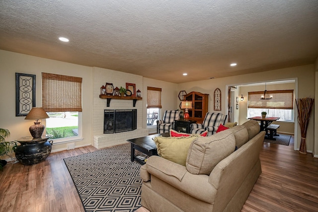 living room featuring recessed lighting, a brick fireplace, a textured ceiling, and wood finished floors