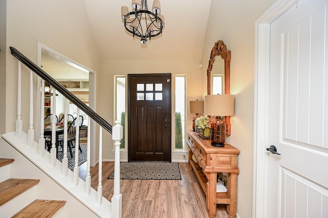 entryway featuring stairs, vaulted ceiling, wood finished floors, and a chandelier