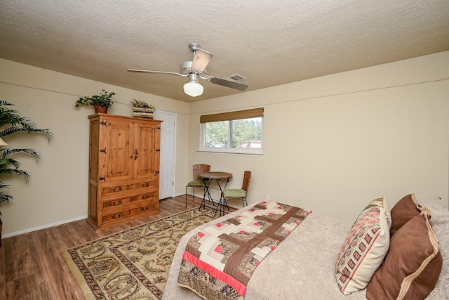 bedroom featuring visible vents, a textured ceiling, a ceiling fan, and wood finished floors