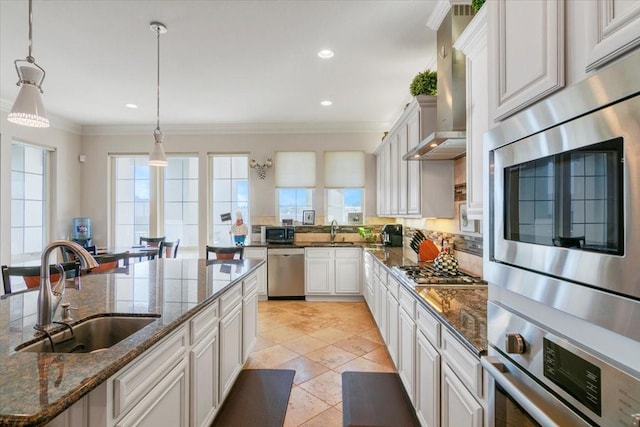 kitchen featuring a wealth of natural light, wall chimney exhaust hood, stainless steel appliances, and a sink