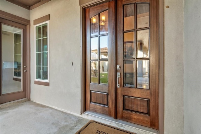 view of exterior entry featuring french doors and stucco siding