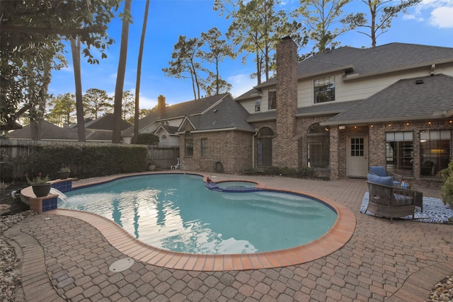 view of pool featuring a pool with connected hot tub, a patio area, and fence