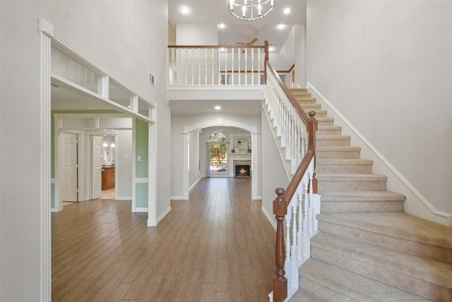 foyer with a warm lit fireplace, baseboards, visible vents, wood finished floors, and stairs