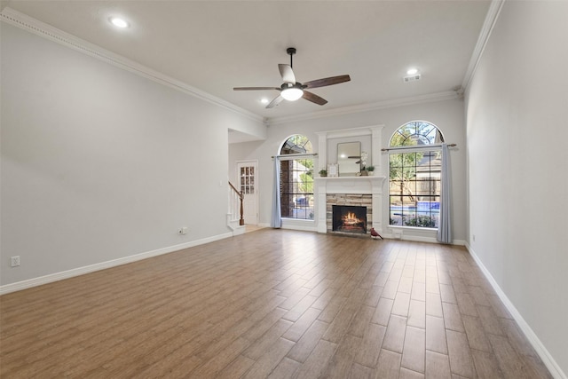 unfurnished living room with visible vents, baseboards, wood finished floors, and a stone fireplace