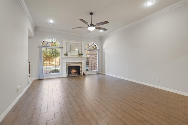 unfurnished living room with a fireplace, wood finished floors, visible vents, baseboards, and ornamental molding