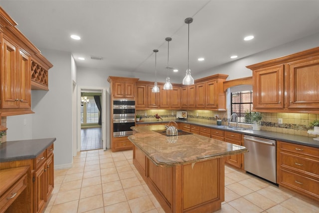 kitchen featuring stainless steel appliances, visible vents, brown cabinetry, a sink, and a kitchen island