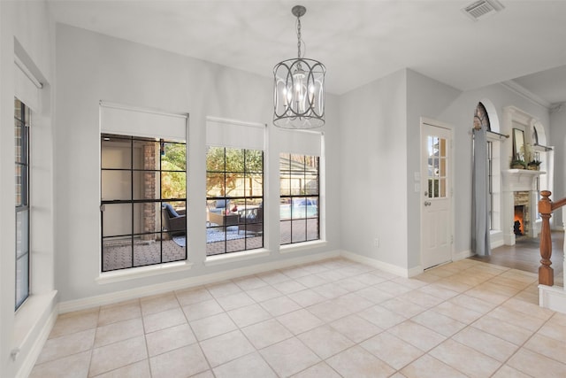 unfurnished dining area featuring a warm lit fireplace, light tile patterned floors, visible vents, and an inviting chandelier